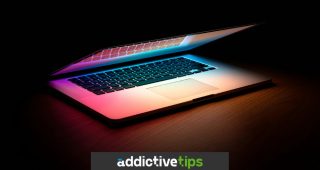 MacBook on wooden table in dim room
